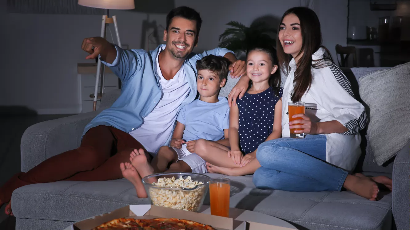 Pais e filhos assistindo TV na sala