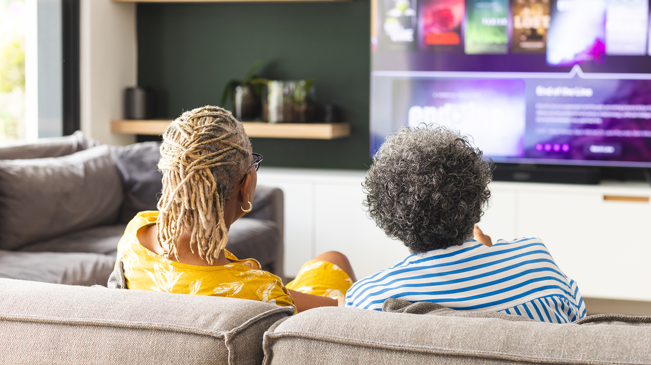 Homem e mulher assistindo TV na sala