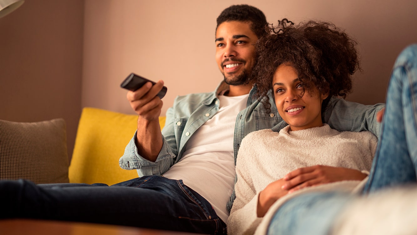 Homem e mulher assistindo TV no sofá