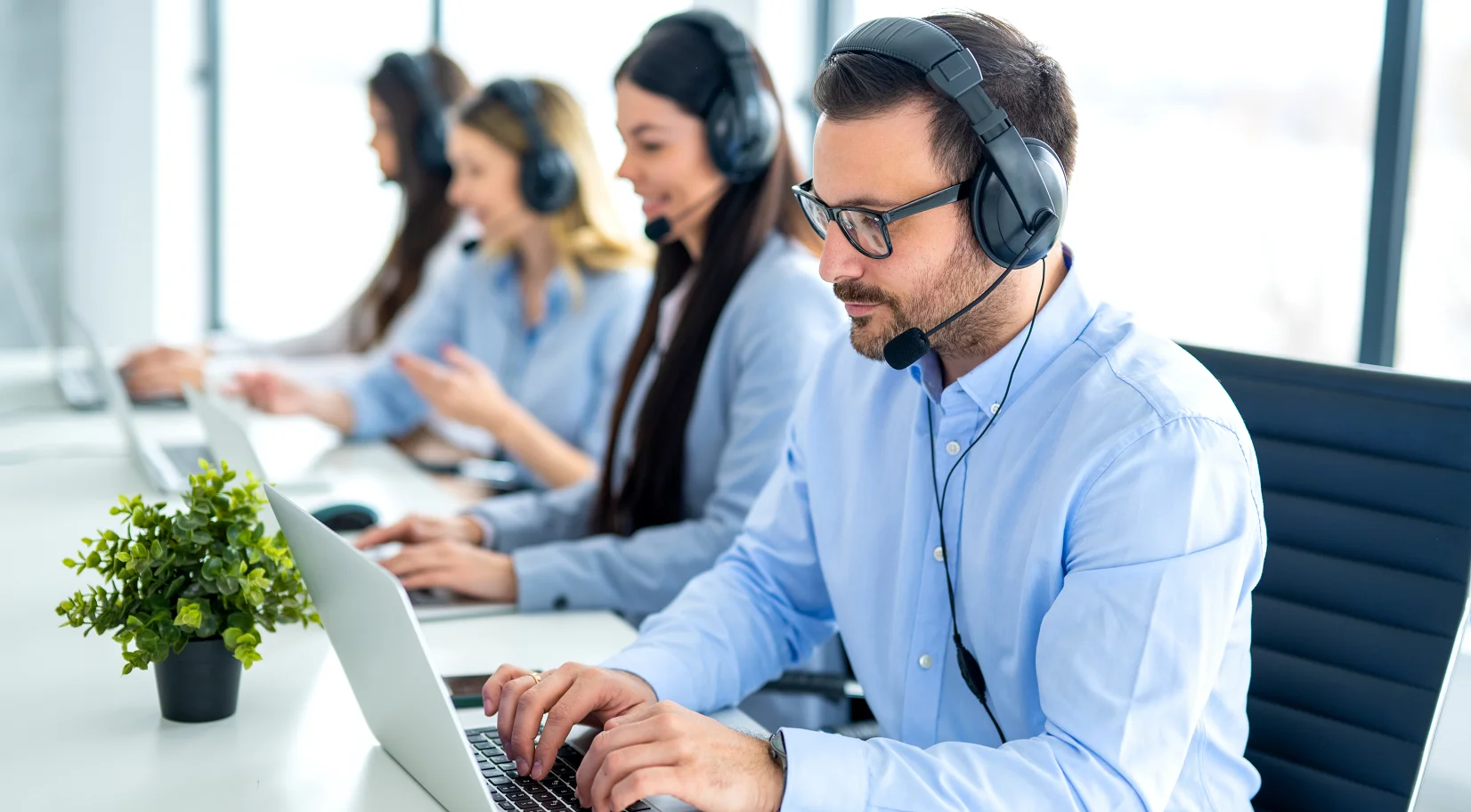 Equipe de atendimento com headset e computadores no escritório