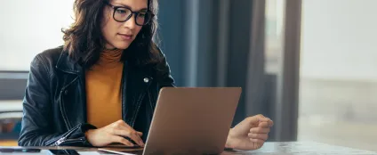 Conectada à internet Oi Fibra, mulher de óculos trabalha usando um laptop