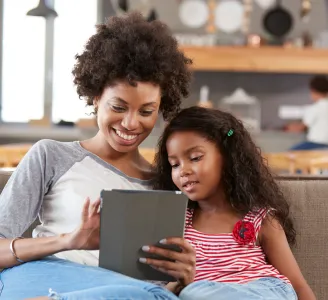 Imagem de uma mãe e sua filha assistindo a algo em um tablet conectado à internet Oi Fibra 500 Mega, sorrindo e compartilhando momentos de diversão.